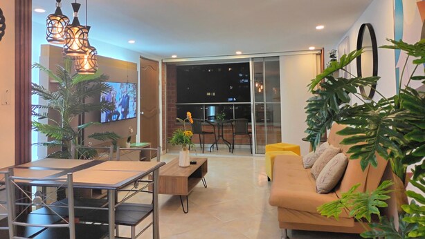 A modern living room with a sofa, coffee table, TV, and plants. - Modern, 3-bedroom, elegant apartment in the best location 402 (Medellín)
