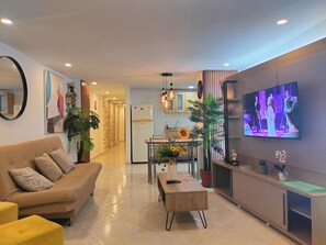 A modern living room with a sofa, coffee table, TV, and kitchen in the background. - Modern, 3-bedroom, elegant apartment in the best location 402 (Medellín)