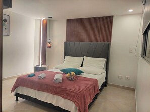 A modern bedroom with a bed, a bedside table, a wall-mounted light, and a window with blinds. - Modern, 3-bedroom, elegant apartment in the best location 402 (Medellín)