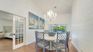 A dining area with a white table and chairs, a chandelier, and a painting of sailboats. - The Gardens Estate - Luxury Resort Retreat Near PGA Golf, Beaches, & Jupiter (West Palm Beach)
