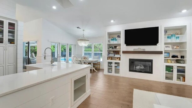 A modern kitchen with a central island, built-in cabinetry, a flat-screen TV, and a fireplace. - The Gardens Estate - Luxury Resort Retreat Near PGA Golf, Beaches, & Jupiter (West Palm Beach)