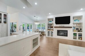 Een moderne keuken met een centraal eiland, ingebouwde kasten, een flatscreen televisie en een open haard.