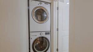 A compact, two-door laundry room with a white door and a white wall.