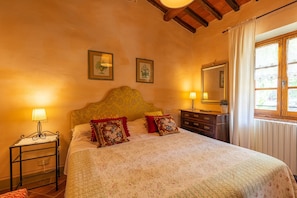 Une chambre à coucher avec un lit, des tables de chevet, une commode et une fenêtre avec des rideaux.