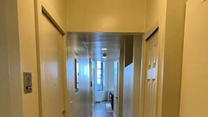 A narrow hallway with wooden flooring, doors on both sides, and a patterned carpet. - Wonderful Fenway 3br/2ba | Steps from Fenway Park! (Boston)