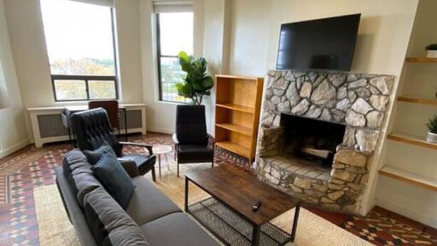 A living room with a sofa, a coffee table, a fireplace, and a TV mounted above it. - Wonderful Fenway 3br/2ba | Steps from Fenway Park! (Boston)