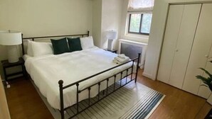 A bedroom with a bed, bedside table, lamp, window, and wardrobe. - Wonderful Fenway 3br/2ba | Steps from Fenway Park! (Boston)