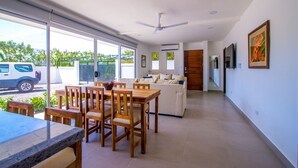 Uma sala de estar ampla com mesa e cadeiras de jantar, um sofá e um ventilador de teto.