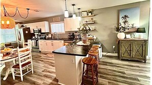 A spacious kitchen with a central island, bar stools, and pendant lighting.