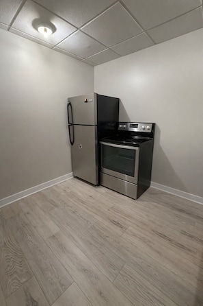 A compact kitchen with a refrigerator, oven, and microwave. - Cozy 2-bedroom apartment in Manorville (Manorville)