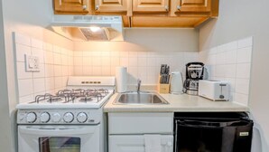 Een functionele keuken met een gasfornuis, spoelbak, broodrooster en vaatwasser.