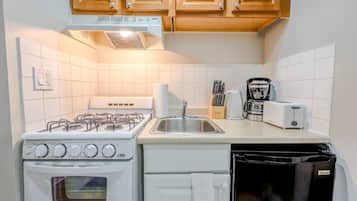 Een oven, een koffiezetapparaat/waterkoker, kookgerei, borden en bestek