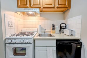 Een oven, een koffiezetapparaat/waterkoker, kookgerei, borden en bestek