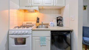 A compact kitchen with white cabinets, a gas stove, a dishwasher, and a coffee maker. - Old Charm Studio Apt near Back Bay (Boston)
