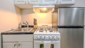 Une cuisine avec des armoires blanches, un réfrigérateur en acier inoxydable, une cuisinière à gaz et un évier.