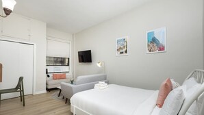 A modern bedroom with a bed, a desk, a chair, and a television. - Centrally Located Basic Studio (Boston)