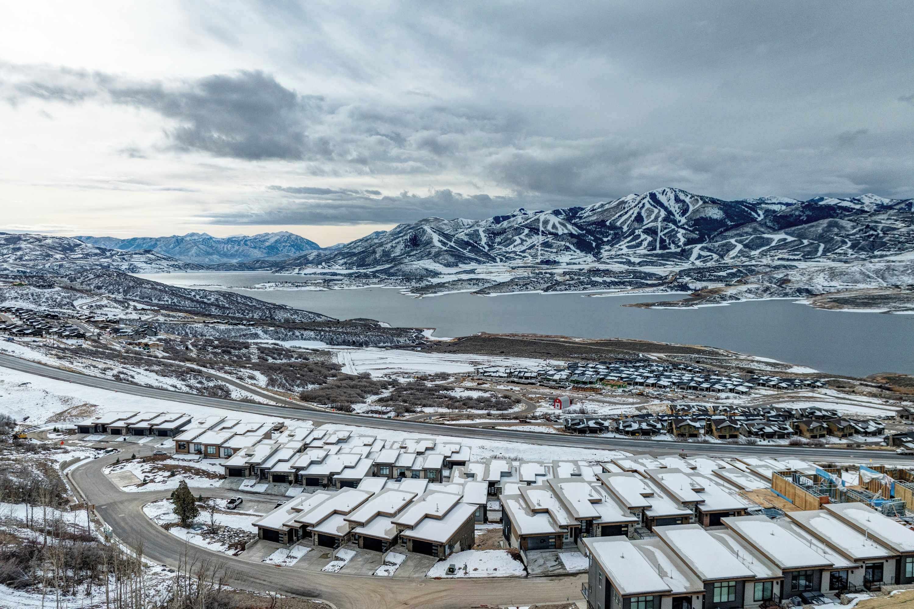 A snow-covered residential area with modern houses and a lake in the background.