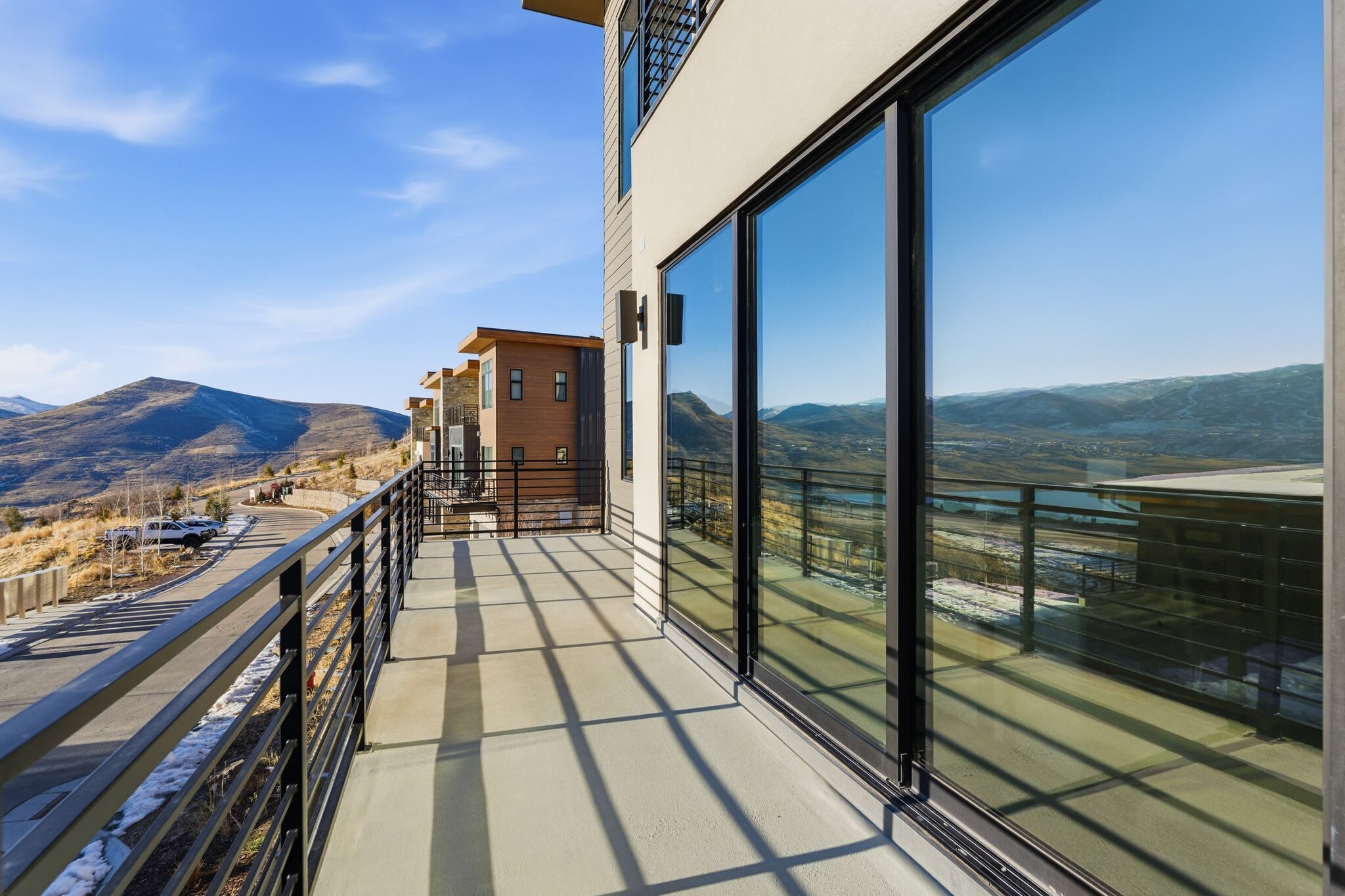A modern building with large glass windows offering a view of mountains and a road.