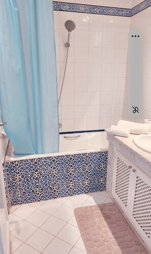 A bathroom with a shower, a bathtub, a sink, and a toilet.