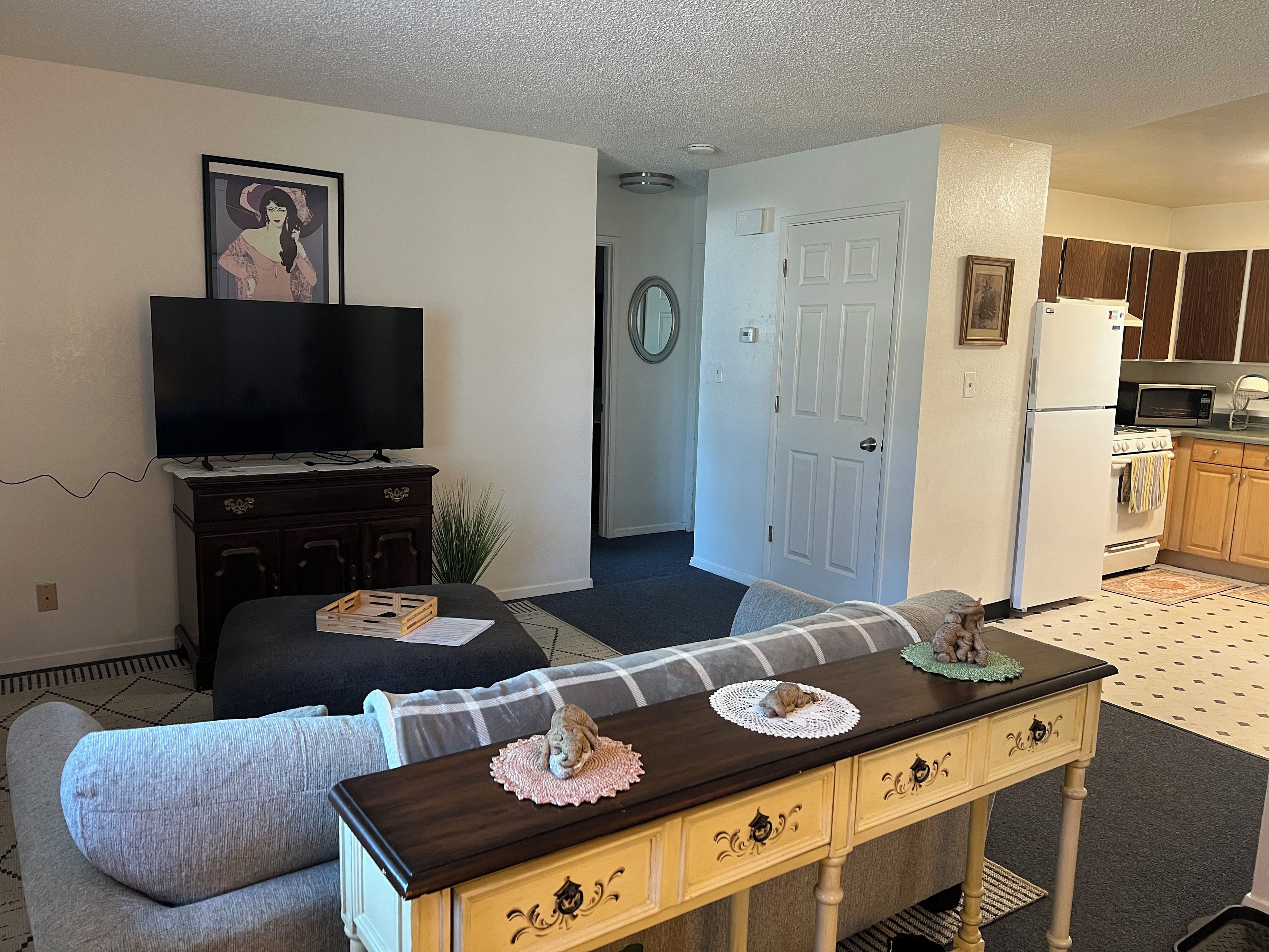 A living room with a television, sofa, and a small table with decorative items.