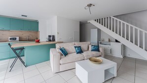 A modern living space with a kitchen, a sofa, a coffee table, and a staircase. - Duplex apartment for 6 people (Arcachon)