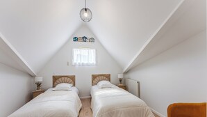 A bedroom with two beds, a window, a radiator, and a hanging light fixture. - Duplex apartment for 6 people (Arcachon)