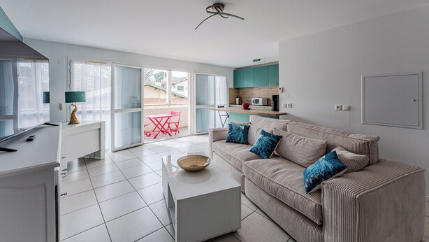 A modern living room with a sofa, coffee table, and a kitchen area in the background. - Duplex apartment for 6 people (Arcachon)