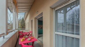 A balcony with red chairs and a table, a window, and a view of a building with a green door. - Duplex apartment for 6 people (Arcachon)