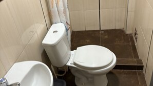 A small bathroom with a toilet, a sink, and a shower curtain. - Hostal - HS Merced (Juliaca)