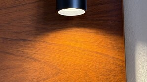 A close-up of a wooden surface with a cylindrical object, possibly a light fixture, casting a shadow. - Hostal - HS Merced (Juliaca)