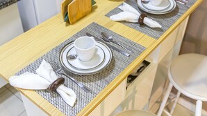 A neatly set dining table with placemats, plates, cups, and cutlery. - Spacious studio apartment with balcony, air conditioning, garage, Wi-Fi, swimming pool, meeting rooms near Paulista Avenue. (São Paulo)