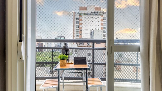 A balcony with a table and chairs, a potted plant, and a laptop. - Spacious studio apartment with balcony, air conditioning, garage, Wi-Fi, swimming pool, meeting rooms near Paulista Avenue. (São Paulo)