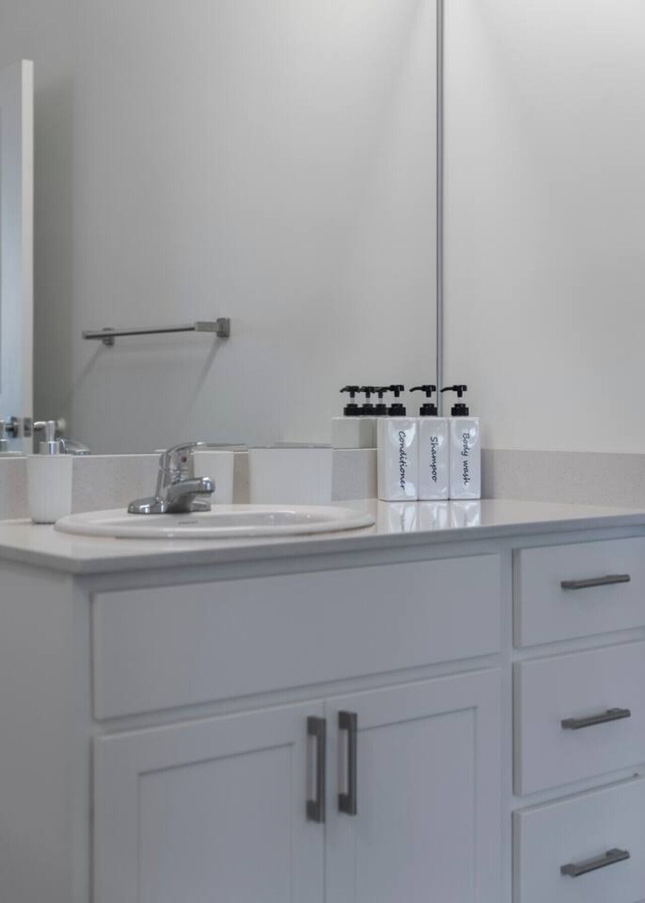 Une salle de bain moderne avec un lavabo blanc, un miroir et un meuble avec des tiroirs.