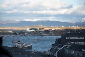 A harbor with boats, buildings, and mountains in the background.