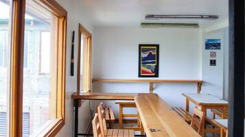 Un aula con pupitres y mesas de madera, un cuadro en la pared y una ventana a la izquierda.