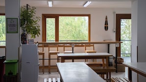 A kitchen area with a breakfast schedule sign, wooden tables, and a plant. - YAGHAN HOSTEL (Ushuaia)