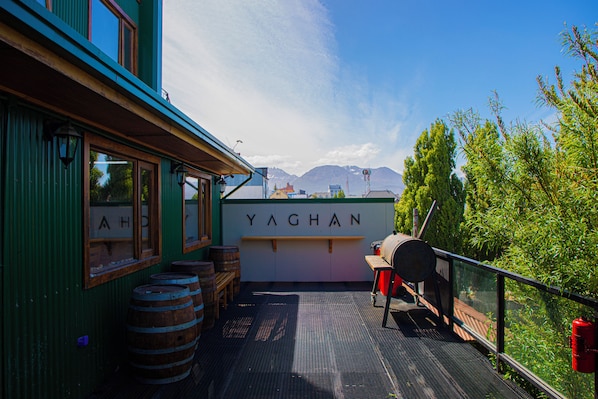 Eine Terrasse mit Holzfässern, einem Grill und einem Schild mit der Aufschrift 'YAGHAN'.