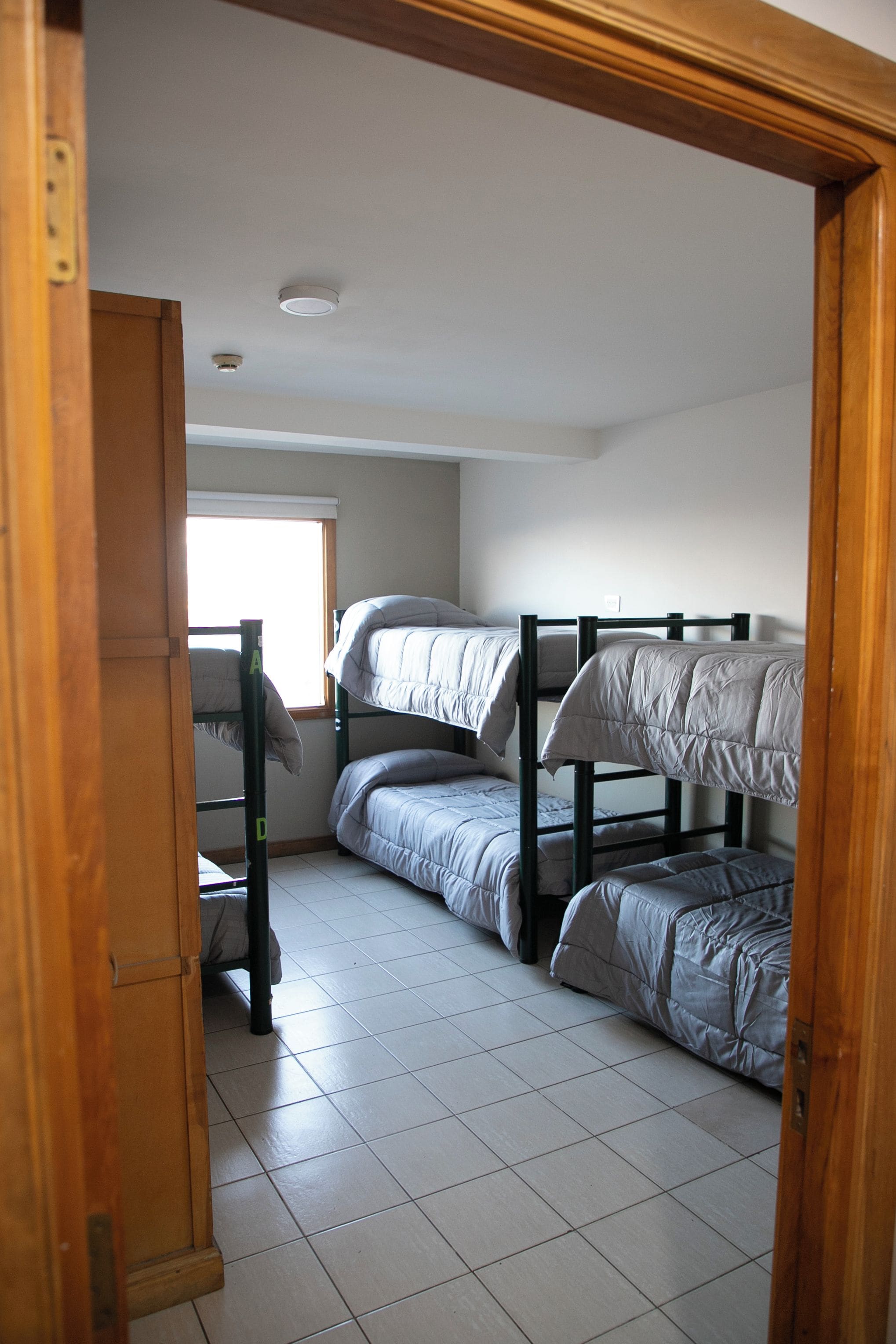 Un dormitorio con literas, una ventana y una puerta.
