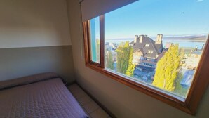A bedroom with a large window offering a view of buildings and trees. - YAGHAN HOSTEL (Ushuaia)