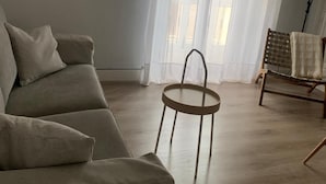 Ein Wohnzimmer mit einer Couch, einem kleinen runden Tisch und einem Sessel mit kariertem Kissen.
