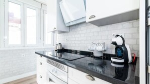 Eine moderne Küche mit weißen Schränken, einer schwarzen Arbeitsplatte und einer Kaffeemaschine.