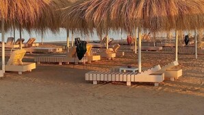 Une plage avec des parasols en chaume et des chaises longues.