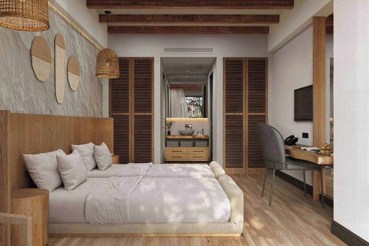 Un dormitorio moderno con una cama grande, cabecera de madera, un escritorio con una silla y un televisor en la pared.