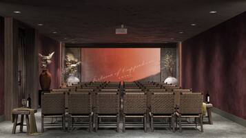 A conference room with rows of chairs, a large screen with text, and decorative vases.