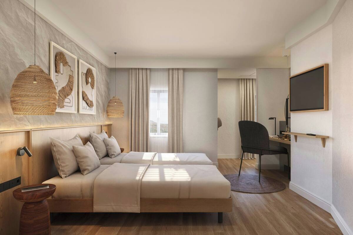 A modern hotel room with a wooden headboard, two beds, a desk, a chair, and a large window with curtains.