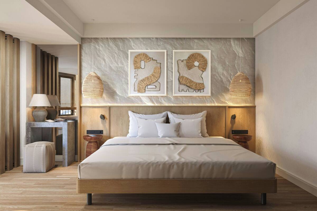A modern hotel room with a large bed, wooden headboard, and two wall-mounted lamps.
