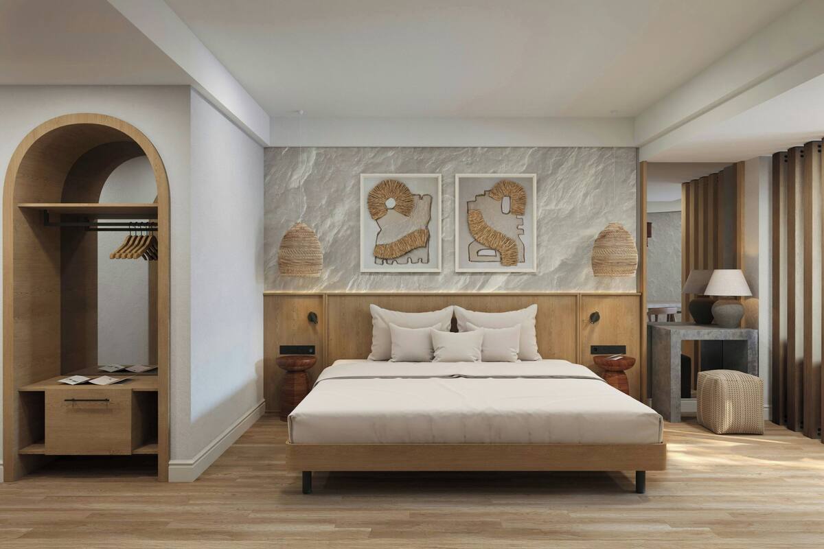 A modern bedroom with a large bed, wooden wardrobe, and a marble wall with two framed artworks.