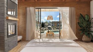 Una camera da letto con un letto grande, travi in legno, una parete in pietra, una finestra e vista su piscina e area esterna.