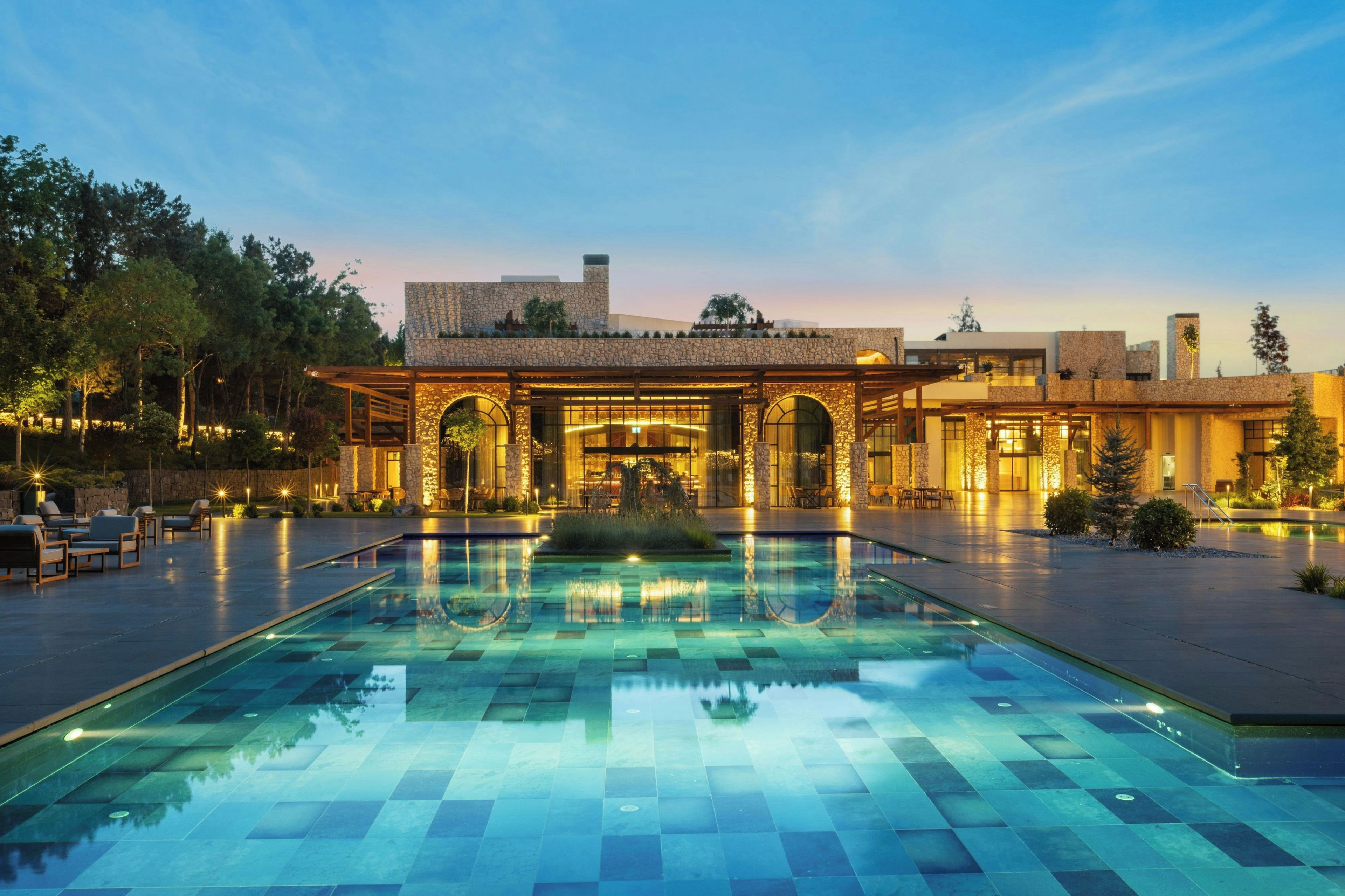 A hotel with a pool, outdoor seating, and a stone facade.