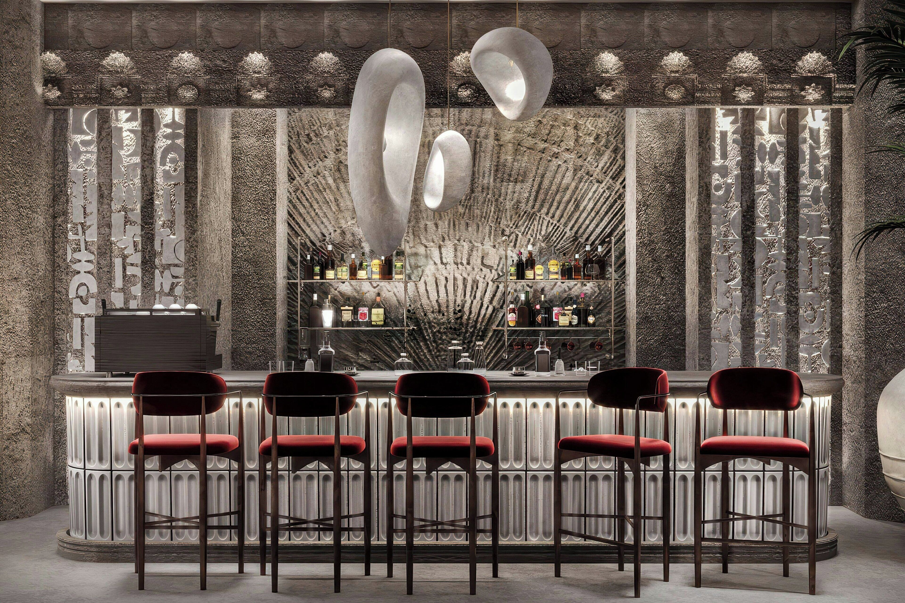 A bar area with a stone wall, bar stools, and a variety of bottles.